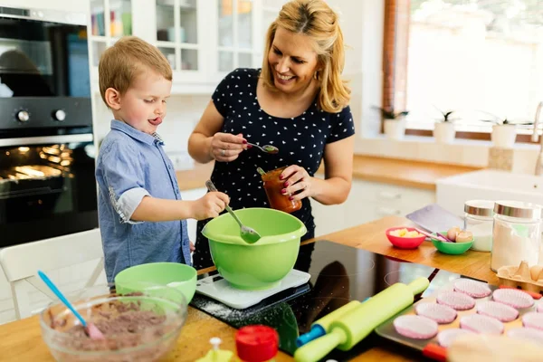 Ребенок помогает матери готовить кексы — стоковое фото