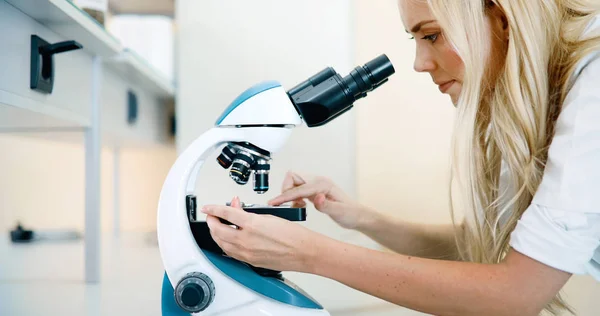 Joven científico mirando a través del microscopio — Foto de Stock