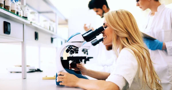 Grupo de cientistas que fazem pesquisa através do microscópio — Fotografia de Stock