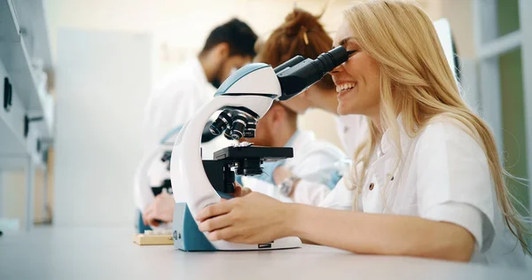 Ung forskare tittar genom mikroskopet i laboratorium — Stockfoto