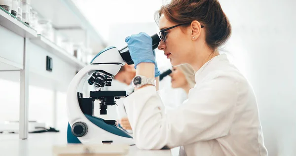 Jovem cientista olhando através do microscópio em laboratório — Fotografia de Stock