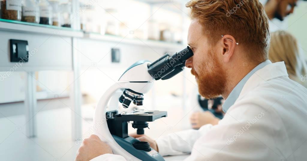 male scientist looking through microscope