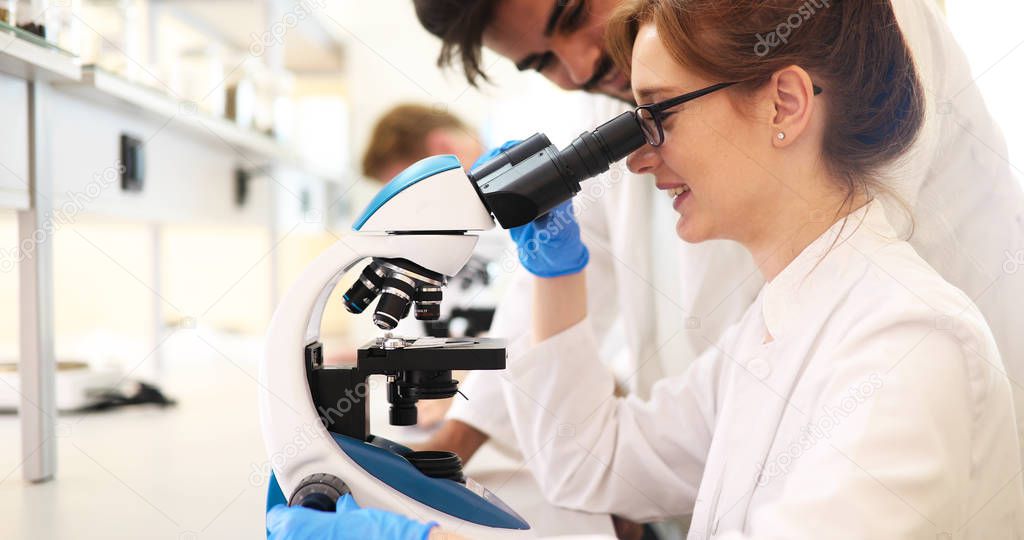 Young scientist looking through microscope 