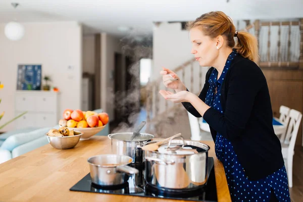 Housewife tasting food  in kitchen — Stock Photo, Image