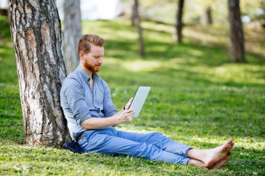 Parkta tablet kullanan bir işadamı