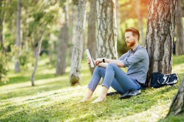 Parkta tablet kullanan bir işadamı