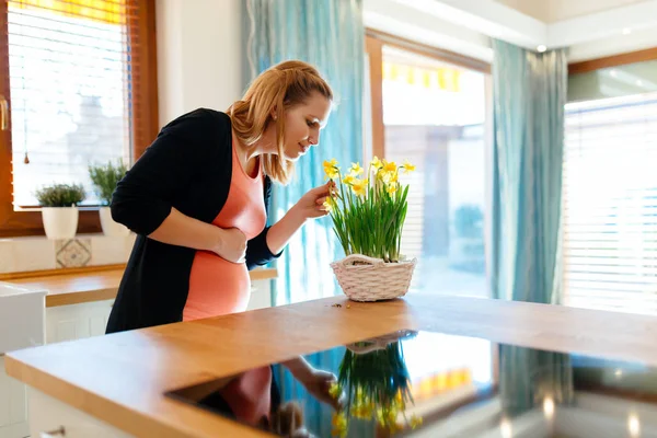 Mujer embarazada cuidando de las flores — Foto de Stock