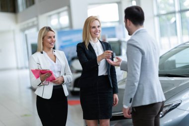 Saleswomen giving key of car clipart