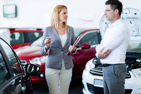 Salesperson selling cars at dealership to buyer — Stock Photo, Image