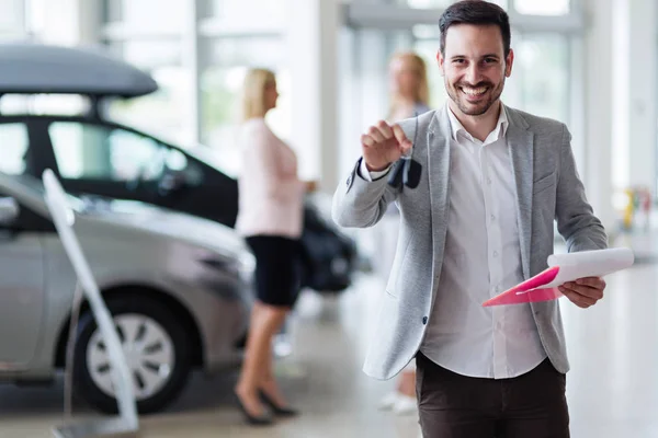 Salesman at car dealership selling vehichles — Stock Photo, Image