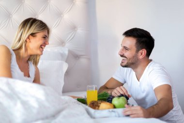 Çift yatakta kahvaltı yapıyor.