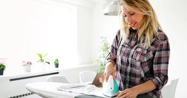 Mujer está planchando ropa en casa — Foto de Stock