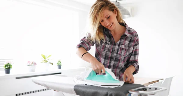 Mujer está planchando ropa en casa — Foto de Stock