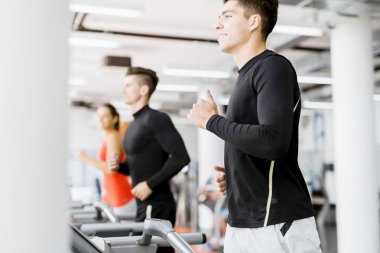 Bir grup genç insan bir fitness merkezinde koşu bandı üzerinde çalışan