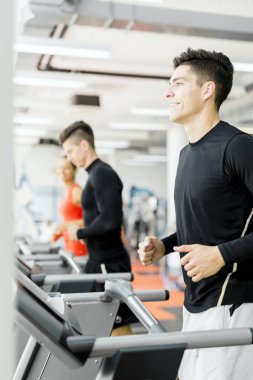 Bir grup genç insan bir fitness merkezinde koşu bandı üzerinde çalışan
