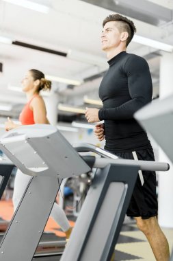 Bir grup genç insan bir fitness merkezinde koşu bandı üzerinde çalışan