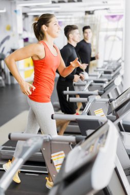Bir grup genç insan bir fitness merkezinde koşu bandı üzerinde çalışan