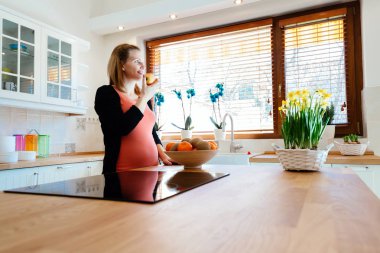 Hamile kadın mutfakta meyve yeme