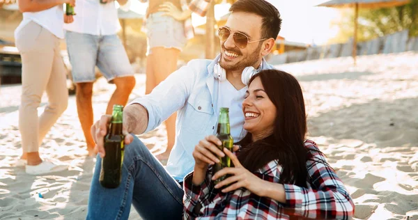 Lyckliga paret leende och druckit öl på stranden — Stockfoto