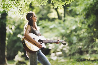 Güzel kadın doğada akustik gitar çalmak