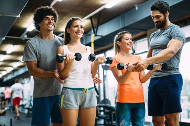 Genç güzel kadın spor salonunda kişisel eğitmenler ile yapıyor