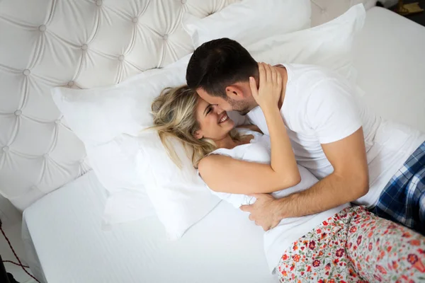 Man och vacker kvinna kysser på säng — Stockfoto