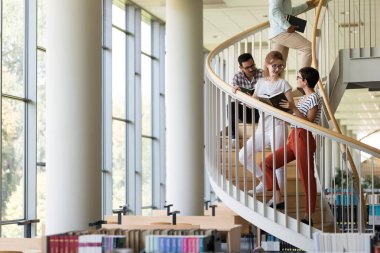 Grup öğrenci üniversite kitaplığında tartışıyor