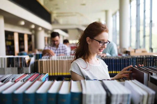 Retrato de una chica muy sonriente leyendo un libro en la biblioteca —  Fotos de Stock