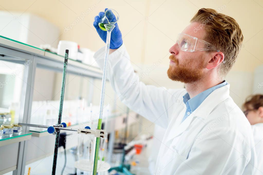 Attractive male student of chemistry working in lab