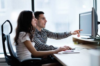 Modern ofis içinde bilgisayar üzerinde çalışan genç iş adamları