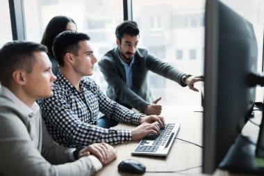 Modern ofis içinde bilgisayar üzerinde çalışan genç iş adamları