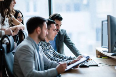 Modern ofis içinde bilgisayar üzerinde çalışan genç iş adamları