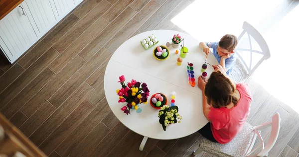 Happy young mother and son are painting Easter eggs — Stock Photo, Image