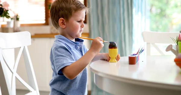 Милый мальчик рисует пасхальные яйца. — стоковое фото