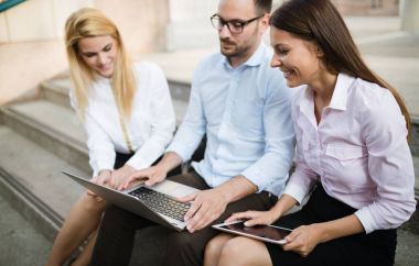 Birlikte laptop çalışma arkadaşları gülümseyerek üç genç