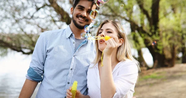 Hermosa joven pareja soplando burbujas de jabón y sonriendo —  Fotos de Stock