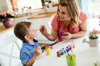 Mutlu genç anne ve oğlu Paskalya yumurtaları boya vardır