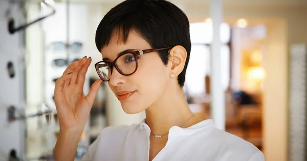 Mujer bastante joven está eligiendo nuevas gafas en la tienda de óptica — Foto de Stock