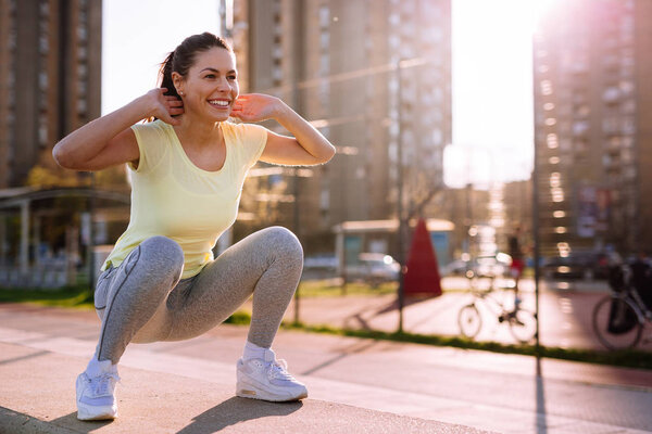 Young woman doing squats in urban area
