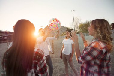 Grup genç neşeli arkadaşıyla kumsalda topla oynamayı