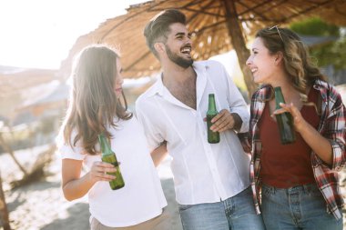 Gülüyor ve sahilde bira içme genç arkadaş grubu