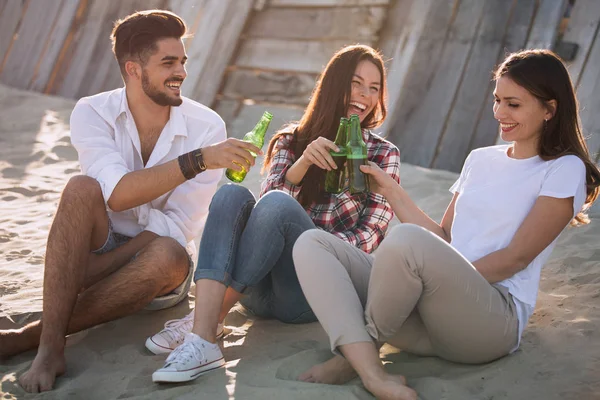 笑いとビーチでビールを飲む若い友人のグループ — ストック写真