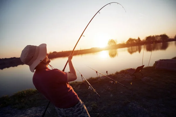 Homens que pescam ao pôr-do-sol e relaxam enquanto desfrutam de hobby — Fotografia de Stock