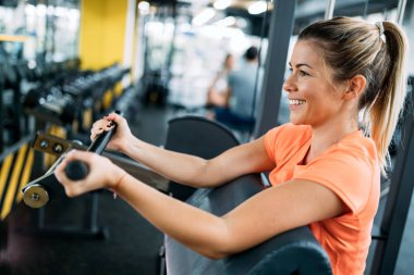 Genç güzel kadın için spor salonunda pazı egzersizleri yapıyor