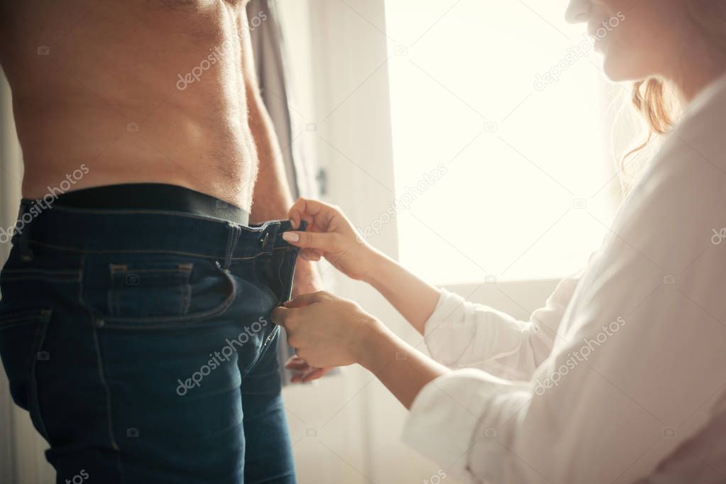 Young beutiful woman unzipping shirtless handsome boyfriend's jeans