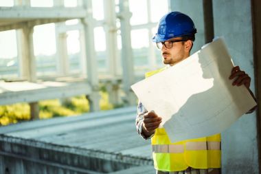 Genç iş adamı inşaat sitesi mühendis mavi baskı ile