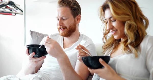 Jovem casal atraente tomando café da manhã na cama — Fotografia de Stock