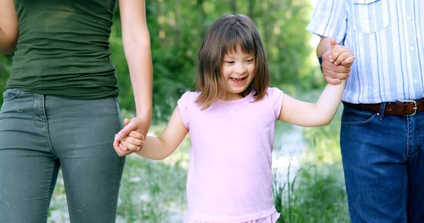Piękna Mała Dziewczynka Zespołem Downa Chodzenie Rodzicami Przyrodzie — Zdjęcie stockowe