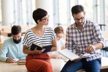 Kütüphanede oturan genç mutlu öğrencilerin görüntüsü