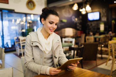 Kafede dijital tablet kullanarak çekici genç kadın